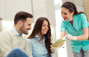 Dental assistant showing smiling couple form