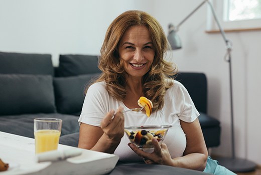 Woman eating fruit salad with dental bridge in Lynchburg