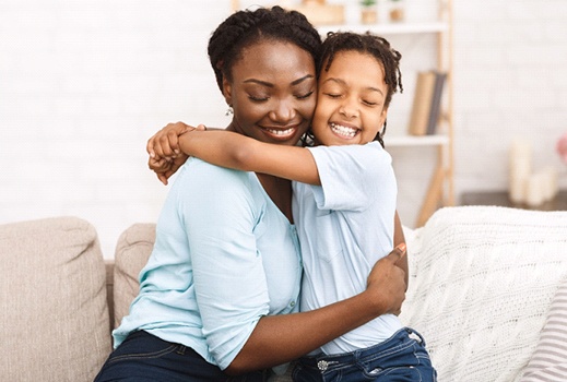 a parent and their child hugging on a couch