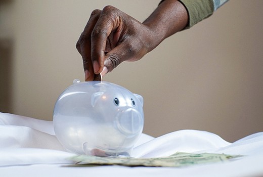 Hand putting coin in piggy bank