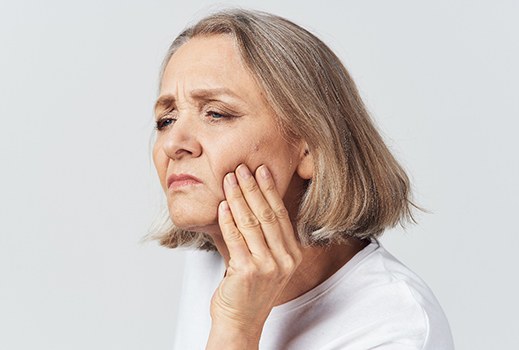 An older woman holding her cheek in pain because of a toothache in Lynchburg