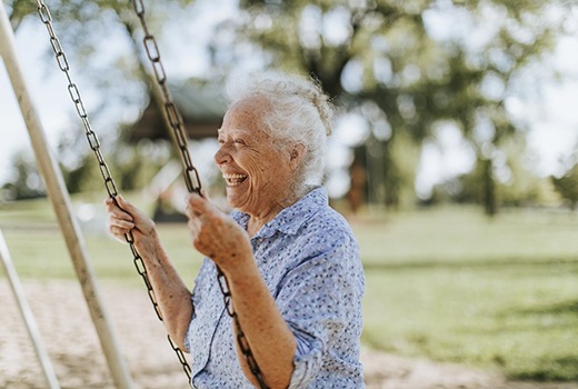 person smiling and swinging at a park