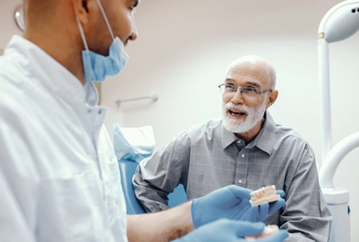 An older man speaking with a dentist.