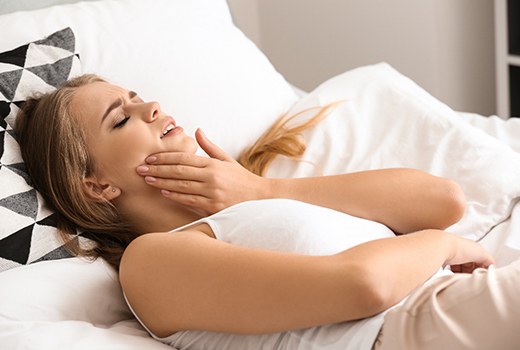Woman in bed with tooth pain