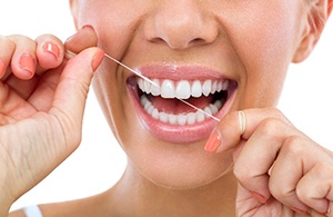 Closeup of woman with white teeth flossing