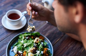 Closeup of man eating well-balanced salad at dining table