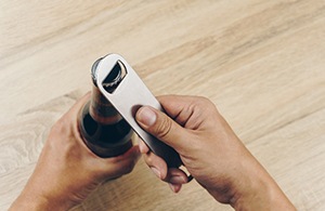 Closeup of patient using bottle opener to open beverage