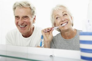 senior couple laughing and brushing teeth