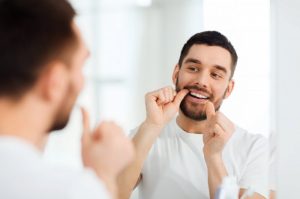 man flossing to prevent a dental emergency 