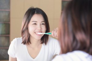 woman with a dental bridge brushing her teeth 