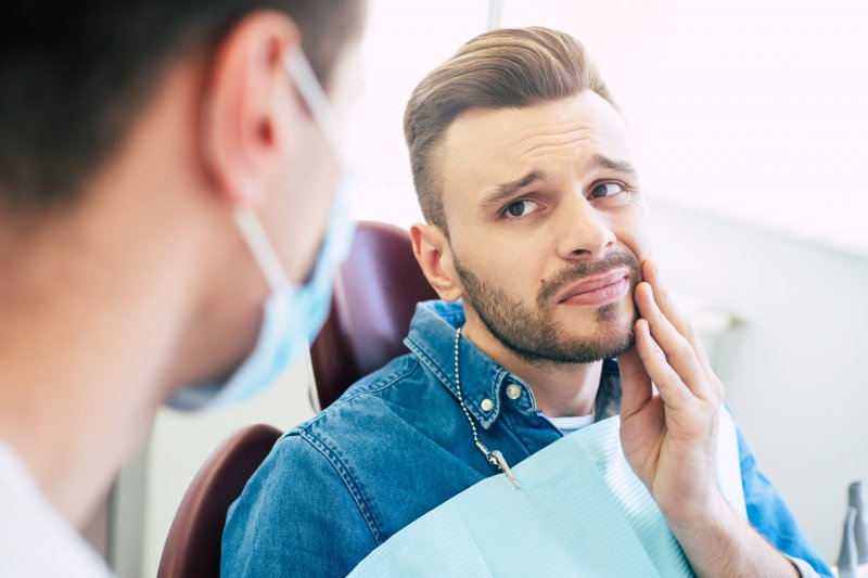 Man rubbing jaw before root canal therapy