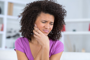 Woman in a purple shirt with one-sided jaw pain