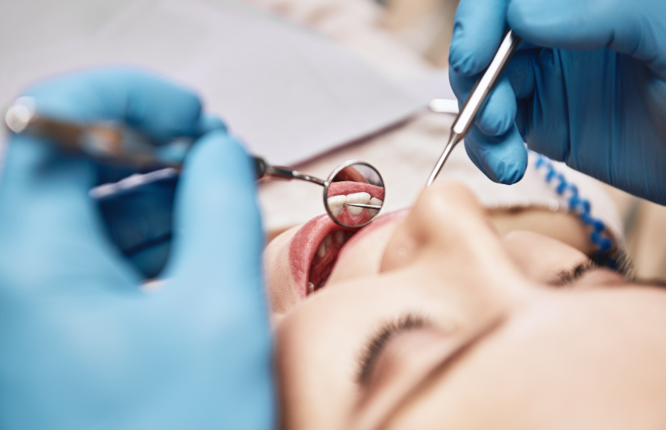 Dentist examining patient's mouth with mirror and pick